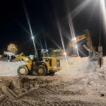 Deroma CAT loader clearing snow at nighttime site