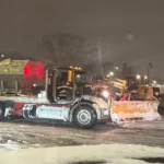 Deroma truck with snowplow during nighttime snow removal